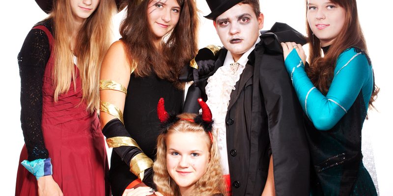 Teenagers dressed in costumes for Halloween against white background.