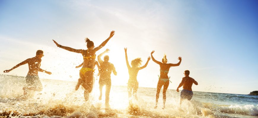 Happy friends jumping in an Orange County Beach.