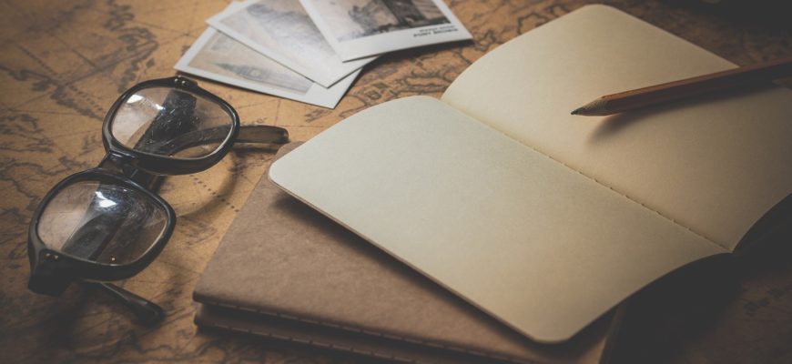 A pair of glasses, notepad, and 2 polaroid photos