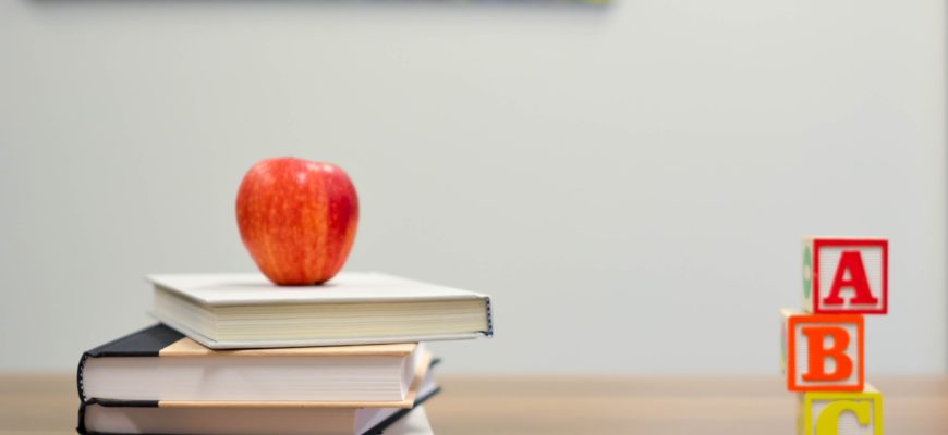 books, ABC blocks, colored pencils, and an apple atop a desk