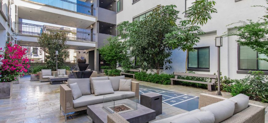 Courtyard with small trees, firepit and outdoor seating.