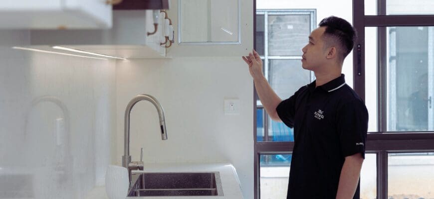 A man inspecting the cabinet storage space in an apartment kitchen