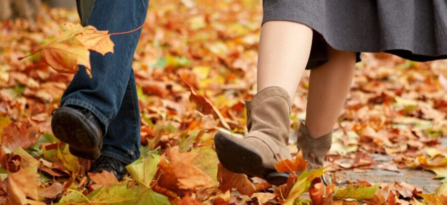 Two people walking through fallen leaves outdoors